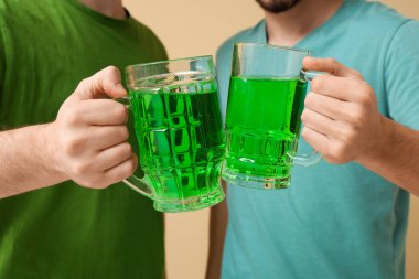 Bej arka planda bira kupaları olan adamlar. Aziz Patrick Günü kutlaması