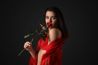 Siyah arka planda gül çiçekli kırmızı iç çamaşırlı seksi genç kadın.