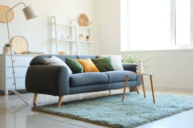 Yastıklı rahat bir kanepe ve oturma odasında vazo olan bir sehpa.