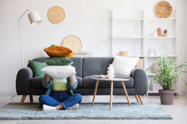 Oturma odasının iç tarafında minderleri olan genç bir kadın oturuyor.