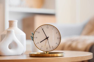 Odadaki sehpanın üzerinde altın çalar saat ve vazolar var. Yakın çekim.