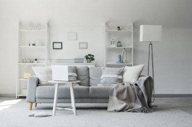 Oturma odasında dizüstü bilgisayarı olan rahat bir kanepe ve kahve masası.