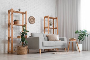 Ahşap raf üniteleri ve oturma odasının içindeki beyaz tuğla duvarın yanındaki kanepe.