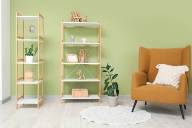 Oturma odasının iç tarafındaki yeşil duvarın yanındaki raf ve rahat koltuk.