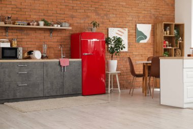 Kırmızı buzdolabı, tezgah ve raflı modern mutfak.