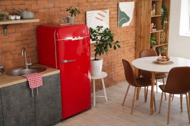 Kırmızı buzdolabı, lavabo ve yemek masası olan modern mutfak.