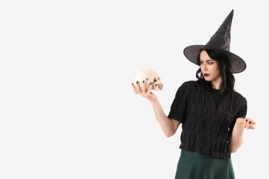 Cadılar Bayramı için cadı gibi giyinmiş güzel bir kadın. Beyaz arka planda insan kafatası izole edilmiş.