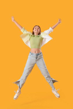Sarı arka planda atlayan genç bir kadın