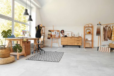 Moda tasarımcısının atölyesinin içinde işyeri, giysi askılığı ve mankeni var.