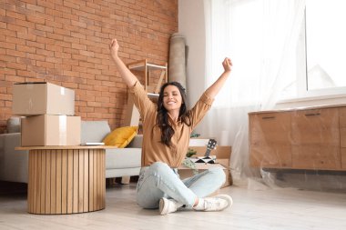 Mutlu güzel kadın taşınma gününde odada oturuyor.