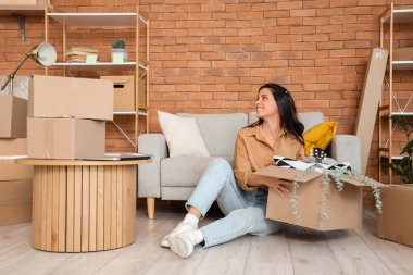 Taşındığı gün elinde karton kutuyla odada oturan güzel bir kadın.