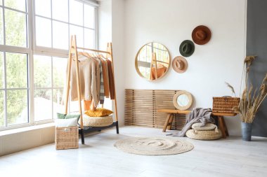 Odanın içinde ahşap bank, elbise askısı ve aynalar var.