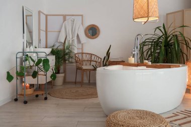 Banyonun içinde küvet, parlayan lamba ve yanan mumlar.