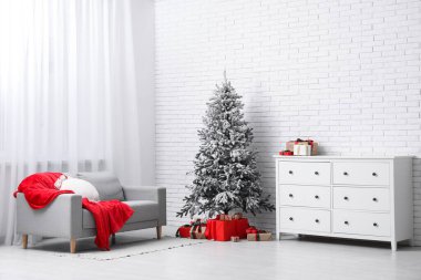 Yastıklı, ekoseli rahat bir kanepe, çekmeceler ve oturma odasının içinde hediyelerle dolu bir Noel ağacı.