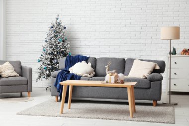 Kanepesi, koltuğu, sehpası ve güzel Noel ağacı olan bir oturma odası.