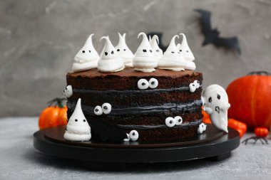 Tatlı Cadılar Bayramı pastası Gri arka planda kremalı hayaletler ve balkabaklarıyla süslenmiş
