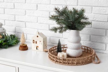 Vazodaki fidan dalları ve beyaz tuğla duvarın yanındaki çekmecelerin üzerindeki Noel süsü.