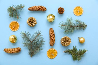 Noel kompozisyonu koniler, dekorasyonlar, köknar ağacı dalları ve mavi arka planda portakal dilimleri. Üst görünüm
