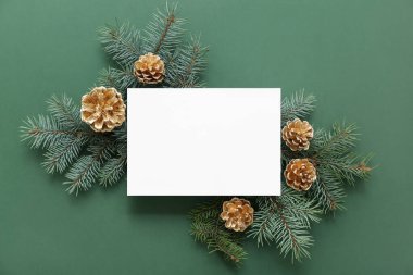 Noel kompozisyonu köknar ağacı dalları, altın koniler ve yeşil arka planda boş bir kart. Üst görünüm
