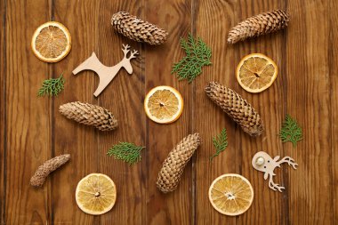 İçinde thuja dalları, koniler, portakal dilimleri ve ahşap arka planda geyik olan Noel kompozisyonu. Üst görünüm