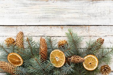 Noel kompozisyonu, köknar ağacı dalları, koniler ve beyaz ahşap arka planda portakal dilimleri. Üst görünüm