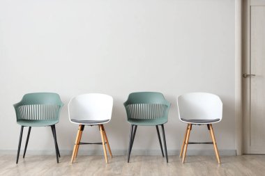 Beyaz duvarın yanındaki modern sandalyeler.