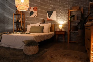 Yatak odasının içinde yatak odası, raf üniteleri, komodin ve parlayan lamba.