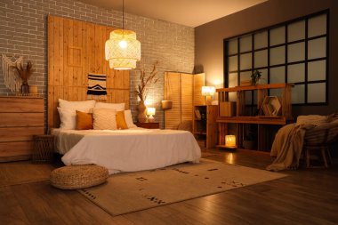 Yatak, çekmece, raf ünitesi ve yatak odasının içinde parlayan lamba.