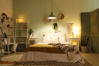 Yatak odasının içinde yatak odası, raf üniteleri, komodinleri ve parlayan lamba.