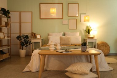 Rahat yatak, komodin, yatak odasının içinde dergi ve dekor.