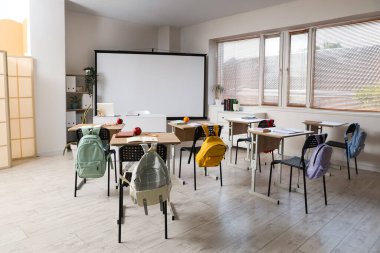 Okul sıraları ve projektör ekranlı sınıfın içi