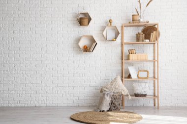 Raflarda kitaplar, mantarlar ve beyaz tuğla duvarın yanında otlar var.