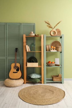 Salonda sonbahar dekorasyonu, gitar ve yeşil katlama ekranlı raf ünitesi