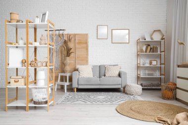 Gri kanepeli, otlu ve raflı aydınlık oturma odasının içi.