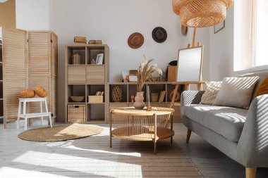 Gri kanepe, sehpa ve ahşap raf üniteleriyle oturma odasının içinde.