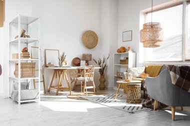 Gri kanepe, balkabağı, çalışma alanı ve raf ünitesiyle aydınlık oturma odasının içinde.