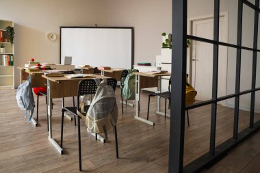 Okul sıraları ve projektör ekranlı sınıfın içi