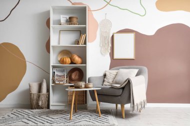 Raflarda gri koltuğu ve balkabağı olan şık bir oturma odası.