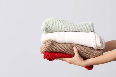 Gri arka planda sıcak giysi yığını olan kadın elleri