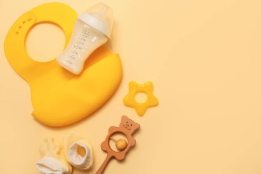 Bebek sütü formülü, önlük, oyuncaklar ve renkli arka planda popolar.