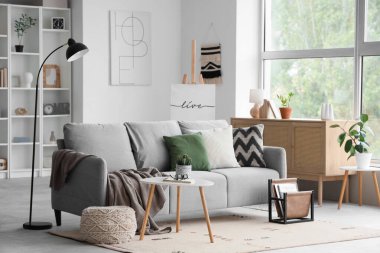 Gri kanepesi, sehpası ve raf ünitesi olan modern oturma odasının içinde.