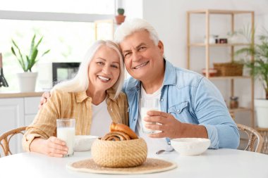 Mutfakta oturan süt ve lezzetli çöreklerle mutlu bir çift.