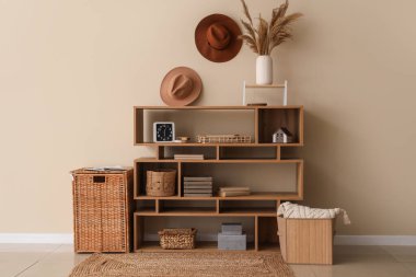 Oturma odasında bej duvarın yanında farklı dekorasyona sahip şık bir raf.