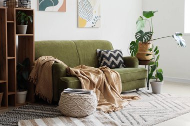 Beyaz duvarın yanında yeşil kanepesi ve raf ünitesi olan modern bir oda.