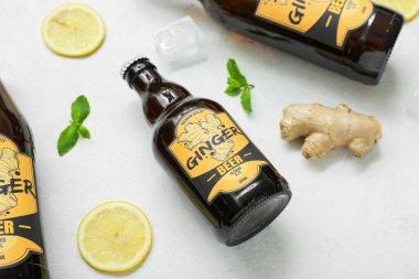 Beyaz arka planda taze zencefilli bira, nane, limon dilimleri ve buz küpüyle kompozisyon, yakın plan.