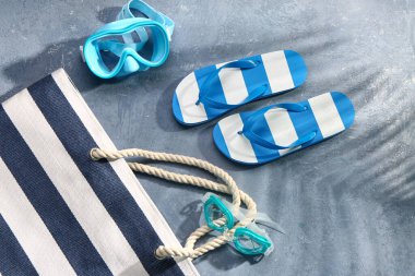 Grunge Blue arka planında plaj aksesuarları olan şık bayan terlikleri.