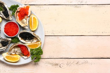 Limonlu lezzetli istiridye tabağı, açık ahşap arka planda siyah ve kırmızı havyar