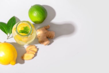 Beyaz arka planda zencefilli ve naneli bir şişe lezzetli limonata.