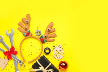 Sarı arka planda Noel süslemeleri, anahtarlar ve hediye kutusu olan kompozisyon