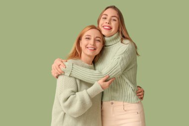 Mutlu genç bir kadın yeşil arka planda annesine sarılıyor. Uluslararası Sarılma Günü